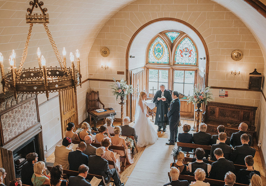 View from above of ceremony with stained glass windows and candle chandelier